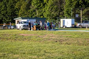 Food vendors and spectators gathered at outdoor event with vehicles parked nearby.