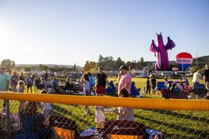 Crowd gathering at an outdoor festival with inflatable decorations and vendor tents.
