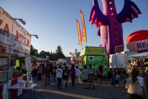 Festival grounds with food vendors and carnival attractions at dusk.