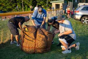 Hot air balloon baskets and equipment being prepared on grassy field.