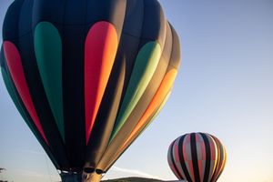 Row of colorful hot air balloons with distinctive striped patterns lined up against the evening sky.