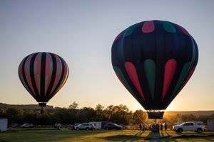 Hot air balloon with striking black, red and green pattern silhouetted against sunset sky.