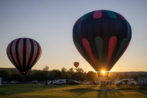 Colorful hot air balloons preparing for launch at dawn in an open field.