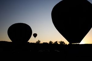 Hot air balloons cast dramatic silhouettes against the evening sky.