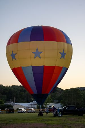 Hot air balloon with blue star pattern design being prepared for flight.