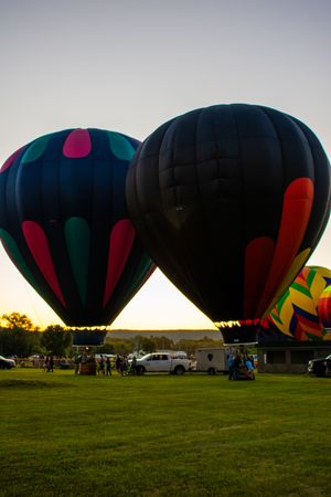 Silhouettes of hot air balloons against a sunset sky at a balloon festival.