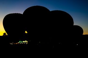 Silhouettes of hot air balloons at dusk with sunset colors in background.
