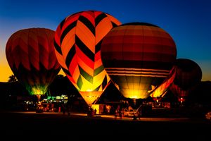 Illuminated hot air balloons creating a dramatic light show against the dark blue sky.
