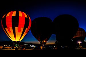 Hot air balloons glowing against the dark night sky during a balloon glow event.