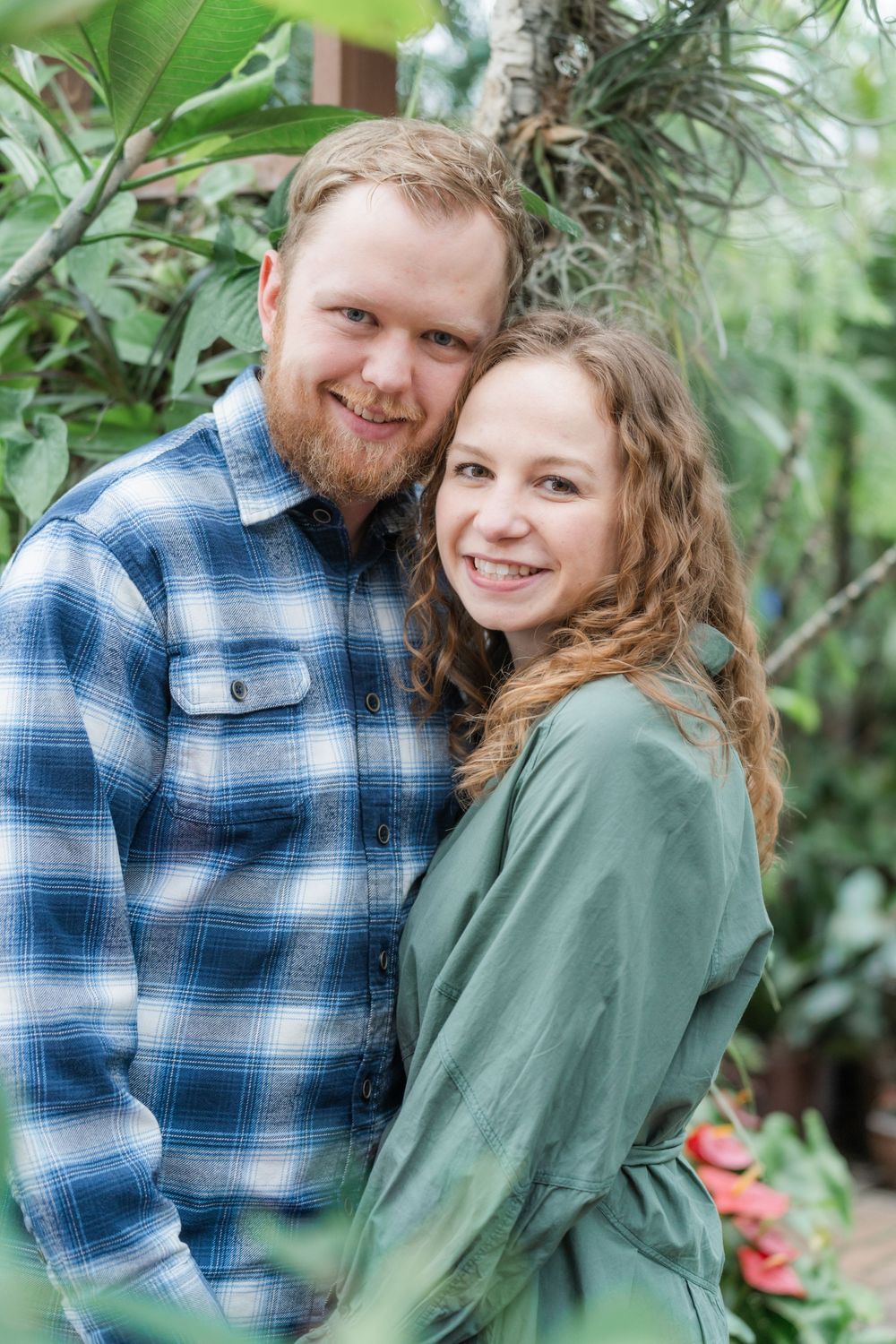 Couple nestled in garden foliage, sharing a quiet moment during their nature-filled engagement session in Minnesota