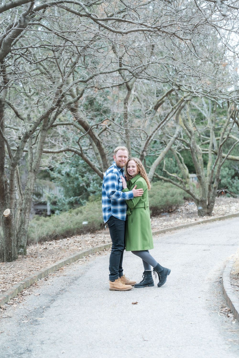Springtime engagement session with natural backdrops of trees, stone paths, and warm tones