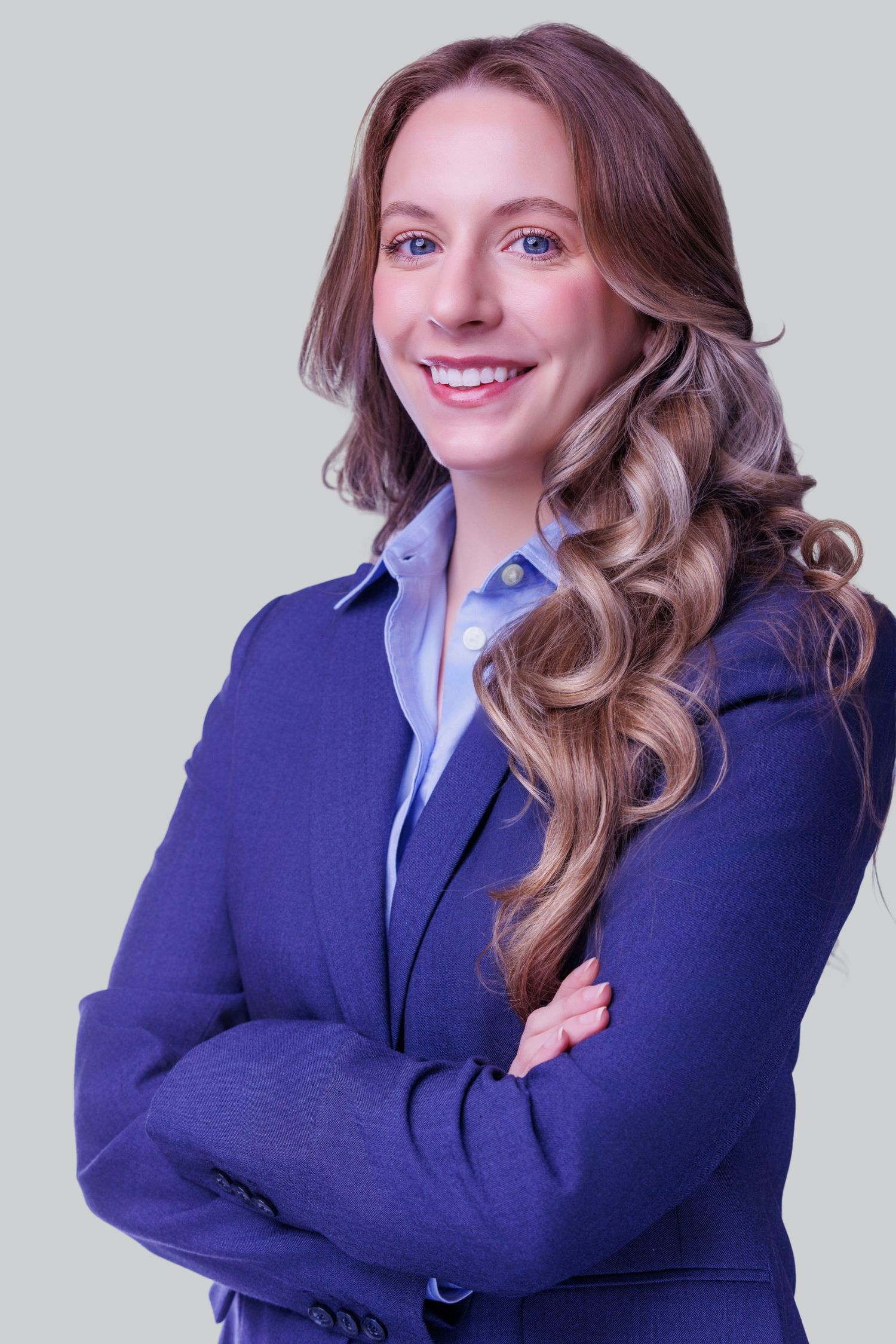 Professional headshot of a smiling woman with shoulder-length brown hair, wearing a blue blouse against a neutral background.
