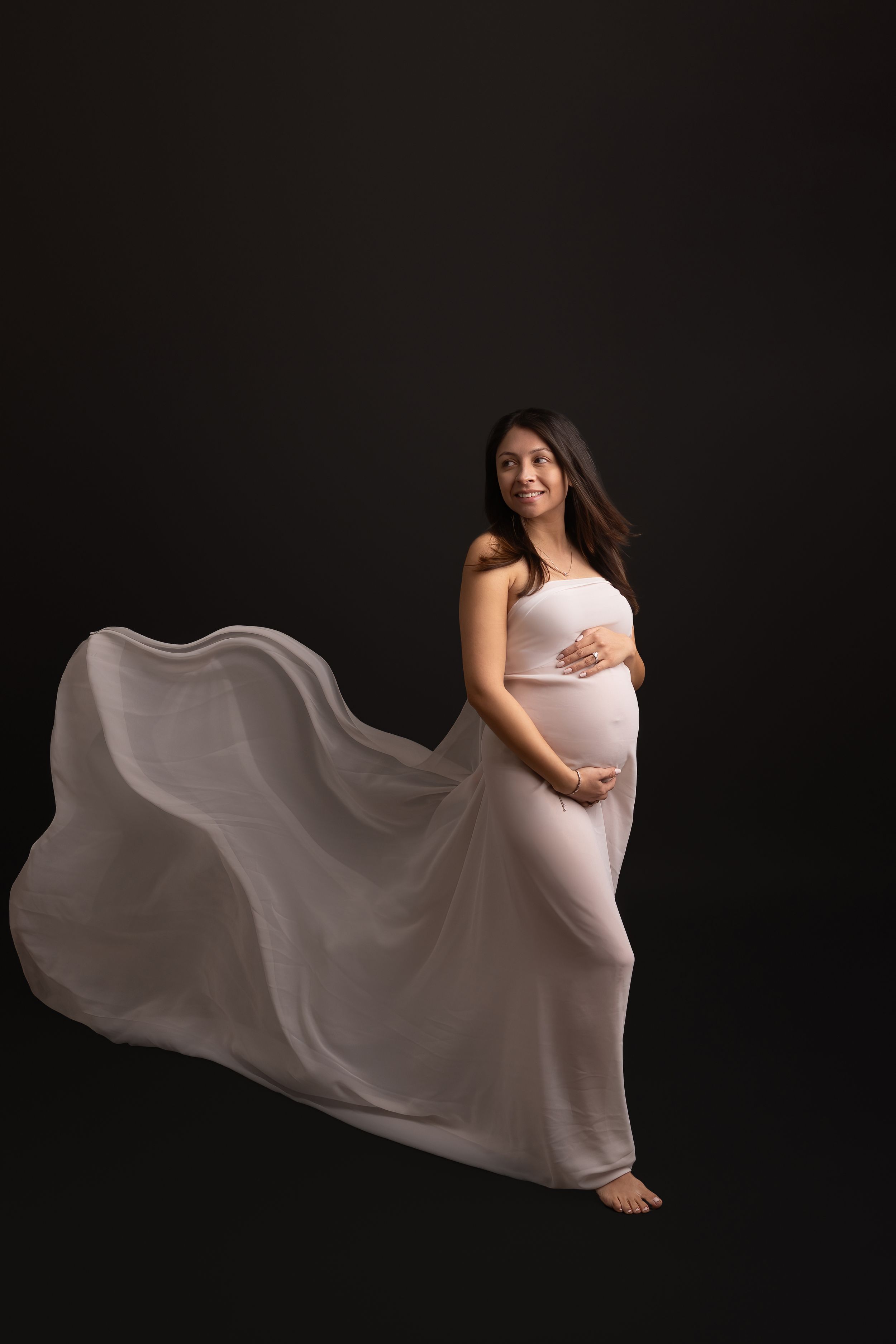 A series of graceful dance poses captured in a dark studio featuring flowing white fabric movement against black background.