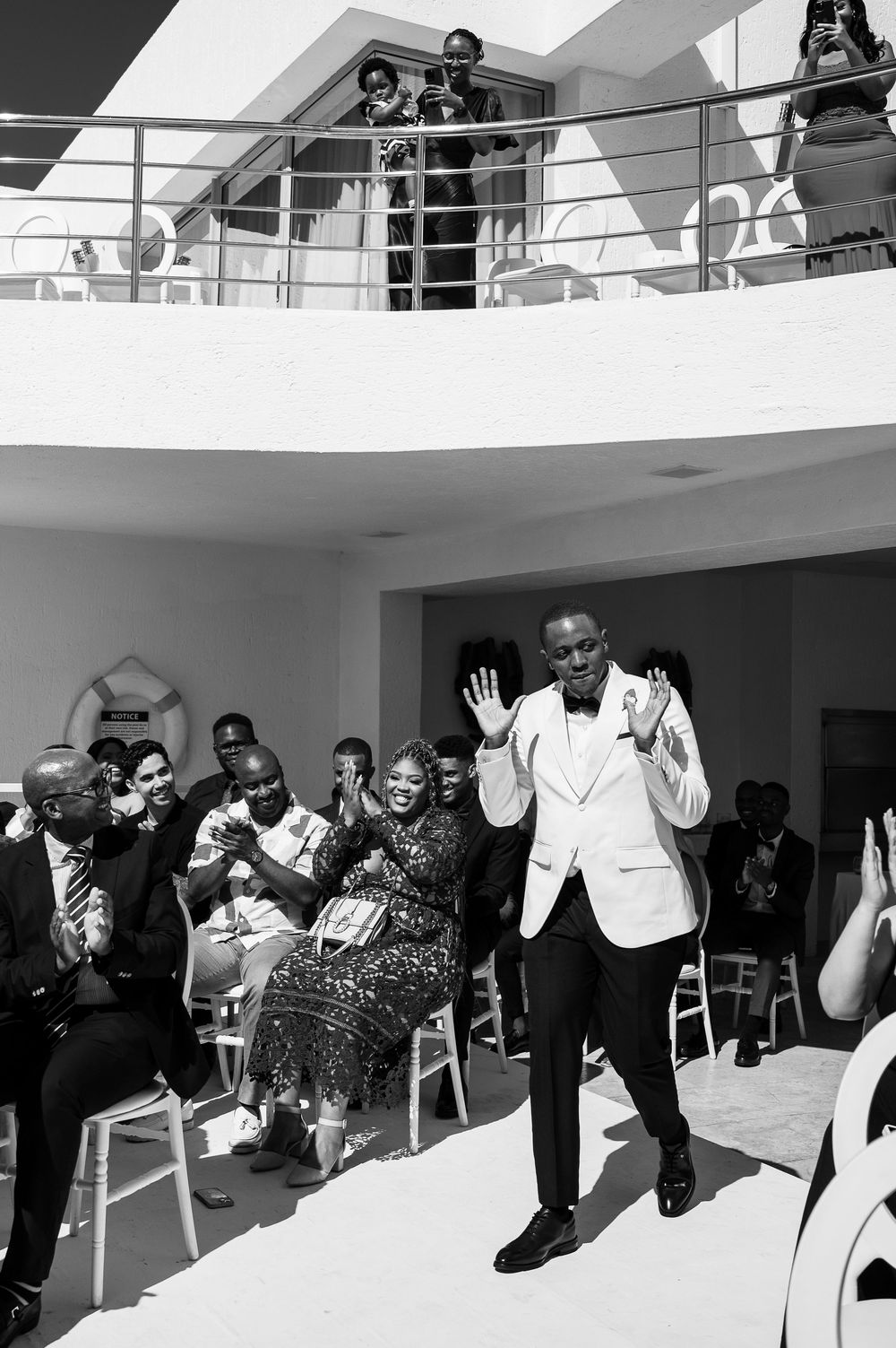 People in formal attire dancing at an event in a bright white studio space during a celebration.