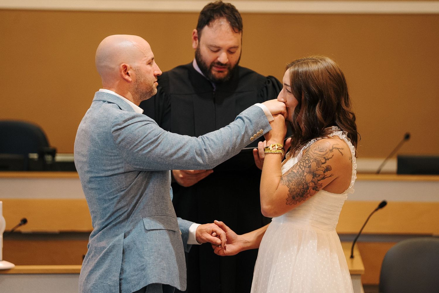 A couple exchanges vows in an intimate courthouse ceremony while an officiant presides over their special moment.