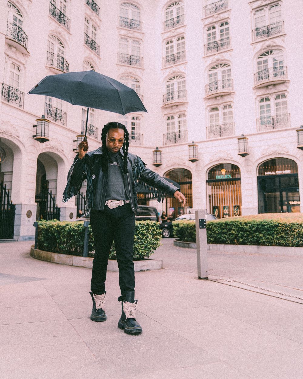 Personne avec un parapluie posant devant la façade élégante d'un bâtiment européen. Florent Vause