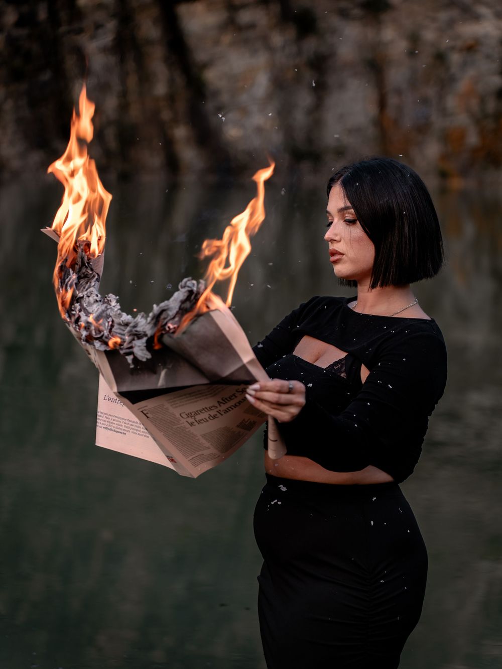 Personnage vêtu d'une tenue noire brûlant artistiquement du papier. Florent Vause