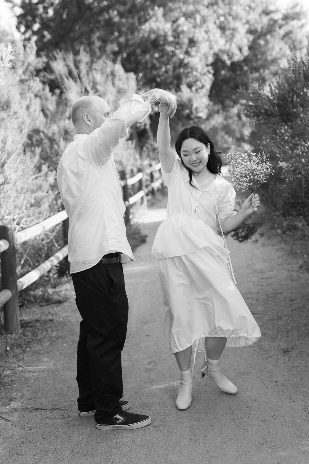 Couple laughing surrounded by historic Ojai oak trees and wildflowers, captured on film.