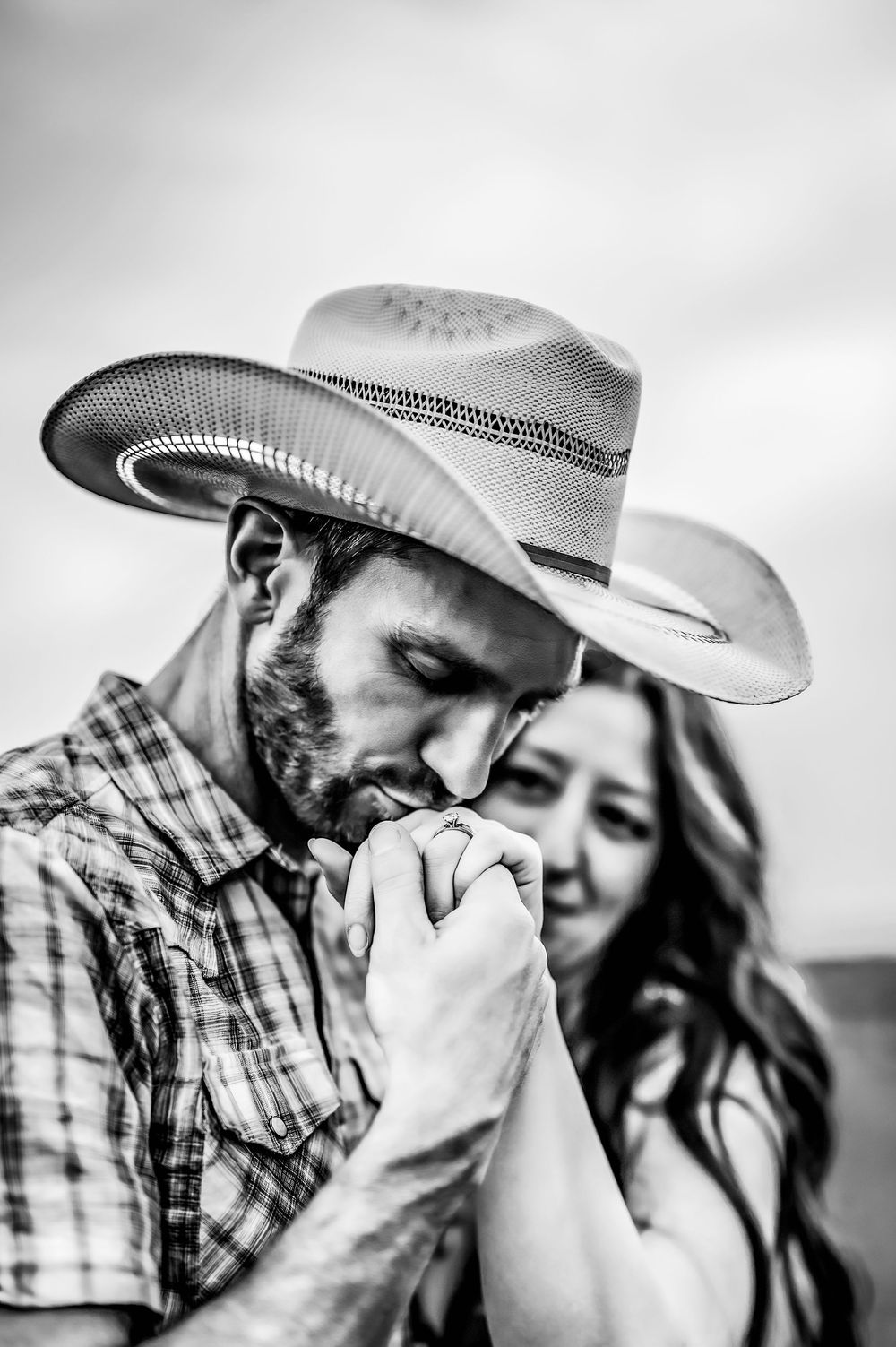 A romantic black and white photograph of a couple sharing an intimate moment, with one wearing a cowboy hat.