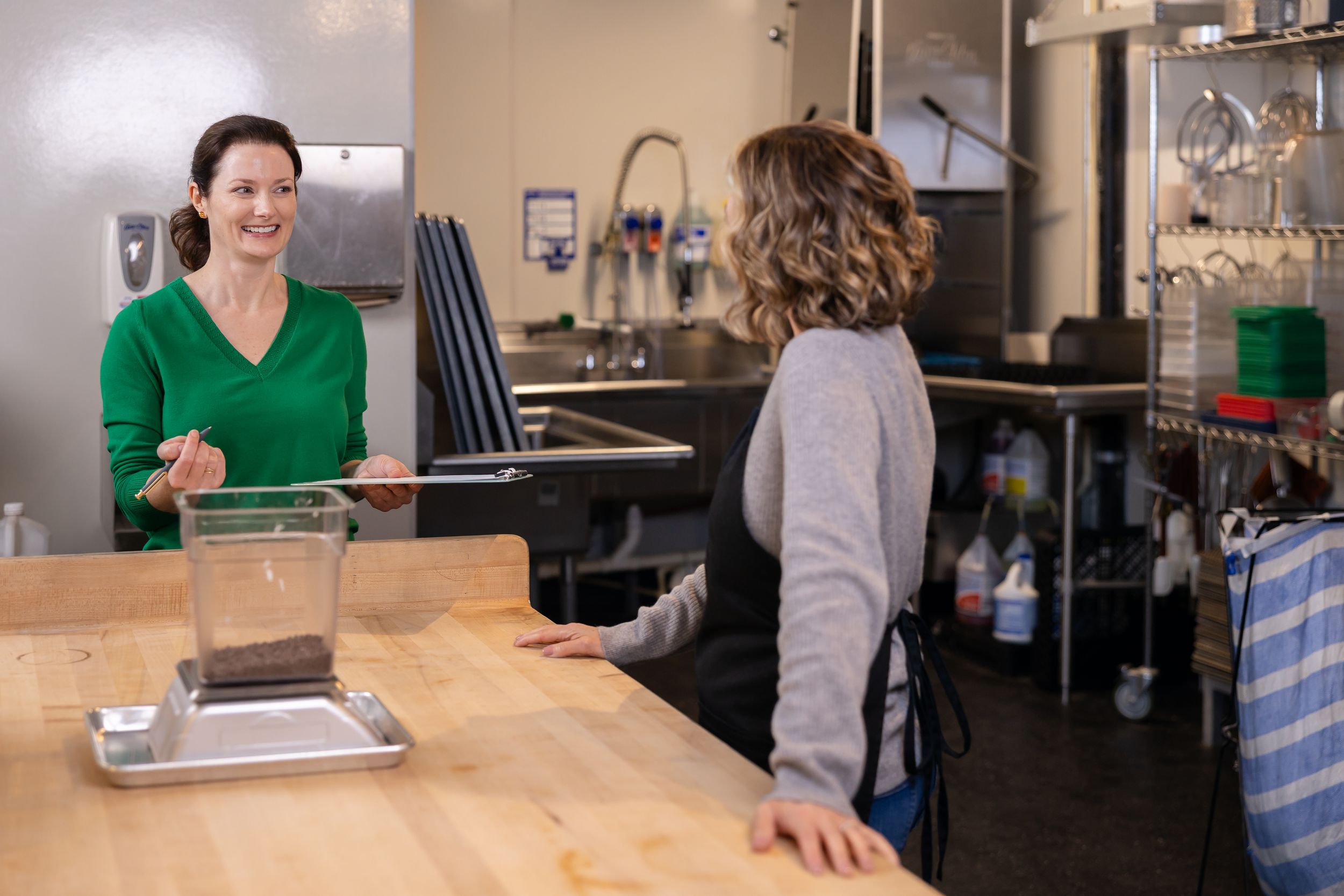 woman business coach Seattle, WA branding in seattle cafe standing with woman while weighing products for quality