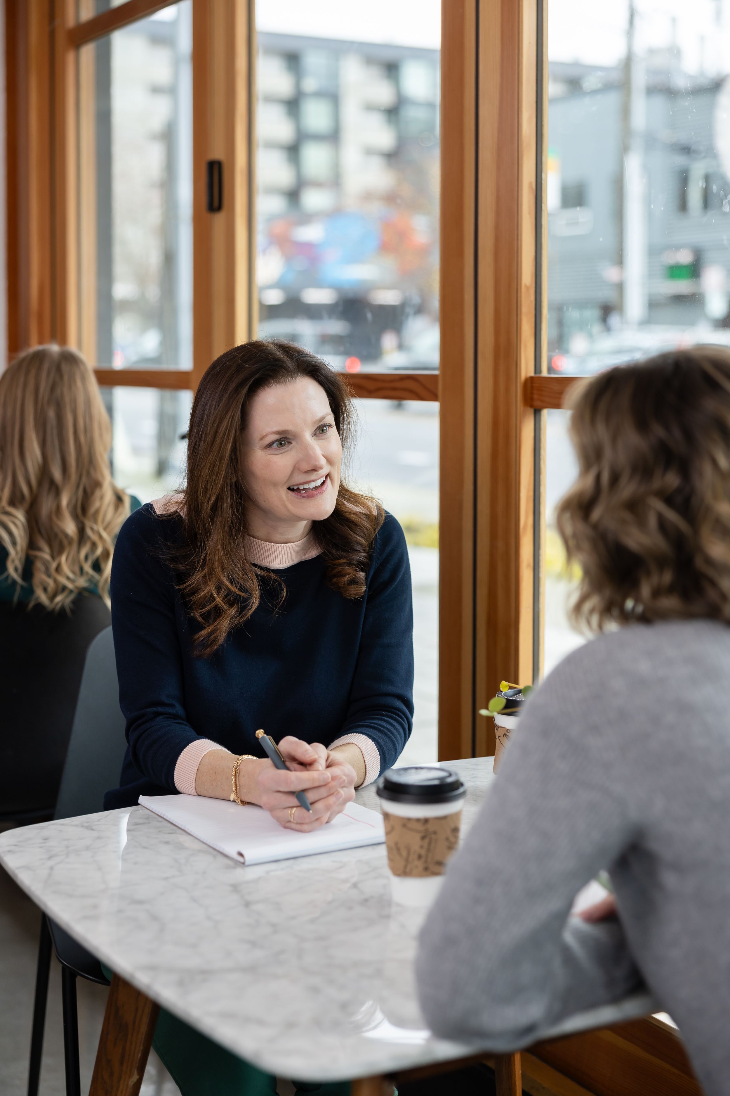 woman business coach Seattle, WA branding sitting at cafe table with woman client discuses business plans and process implementation