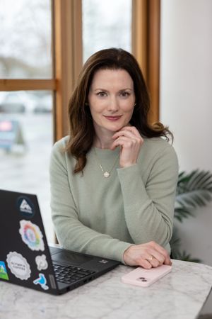 woman business coach Seattle, WA branding lifestyle sitting at cafe table with laptop open