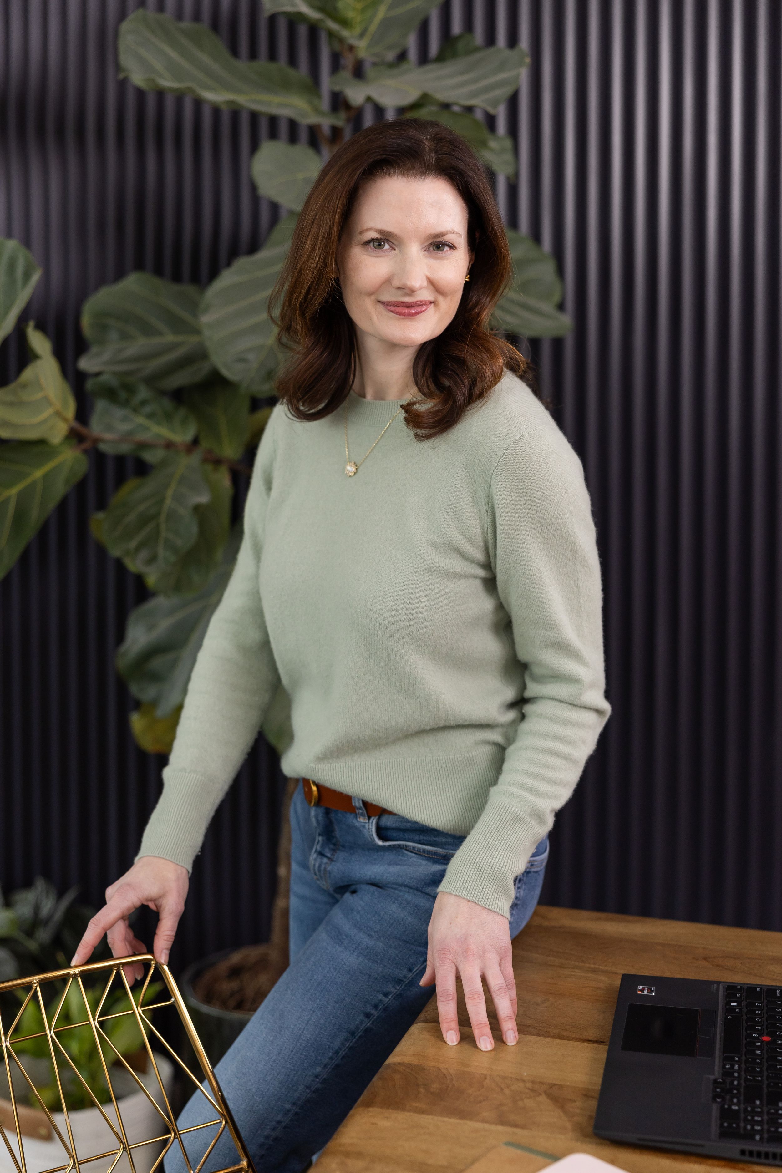 woman business coach Seattle, WA branding standing at conference table with laptop open looking and smiling at camera