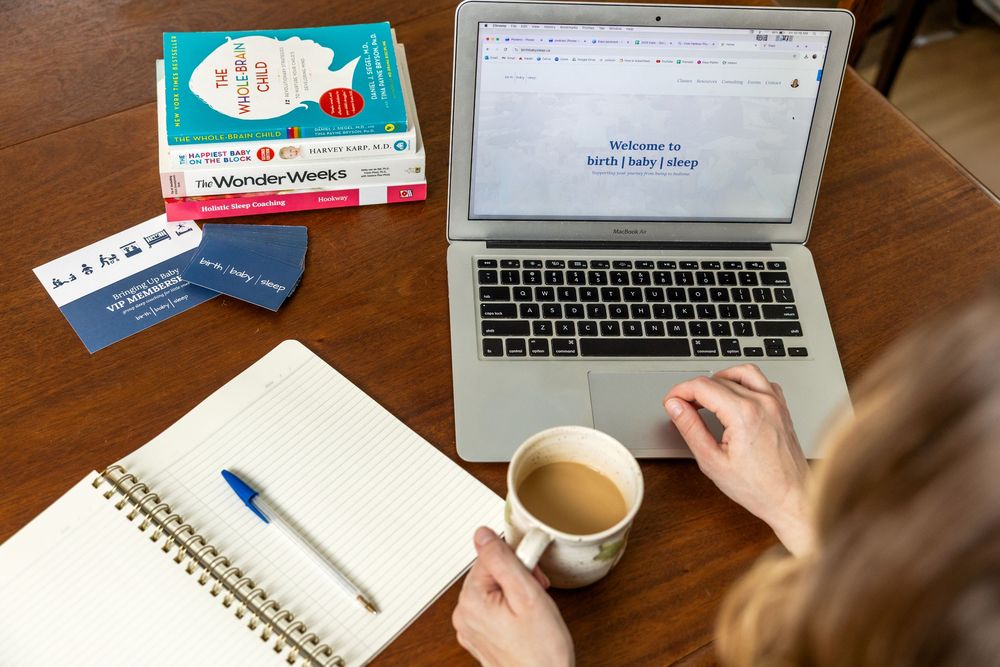 Overhead view of laptop, notebook, coffee cup and tea boxes on wooden desk during work session.