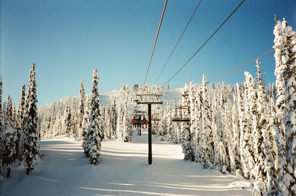 Snow-covered ski lift towers and lines stretch across a winter mountain landscape.