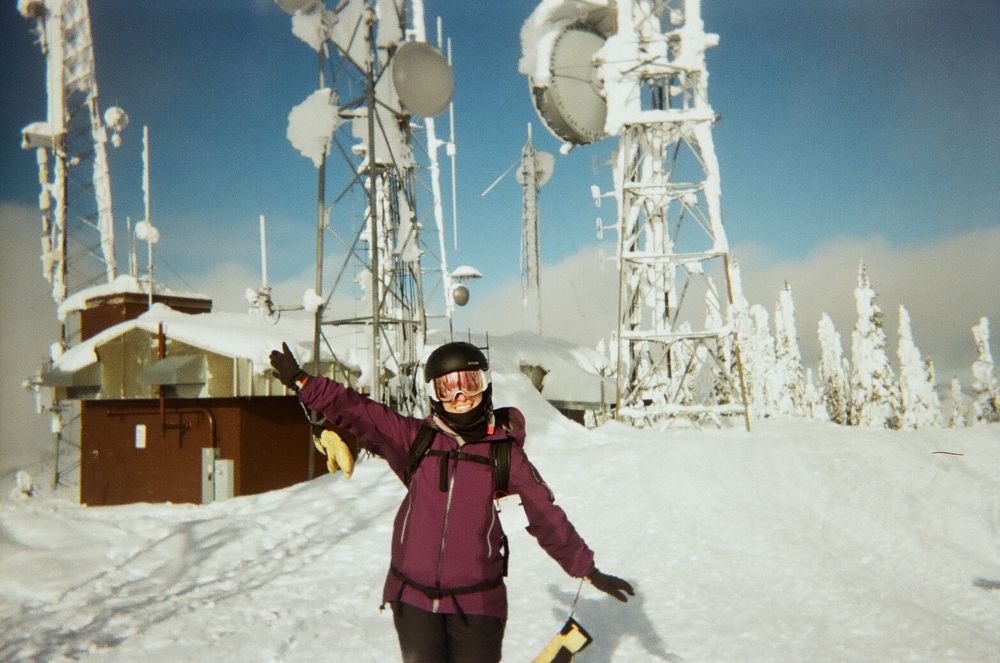 Snow-covered communication towers and winter landscape at a mountain summit.