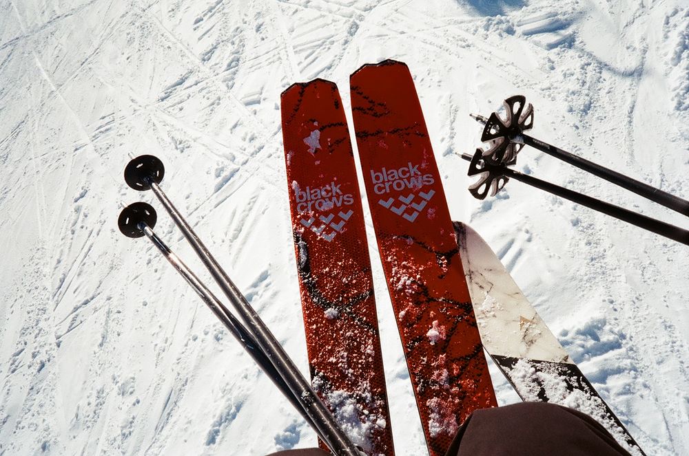 Close-up of red ski equipment and poles on snow-covered ground.
