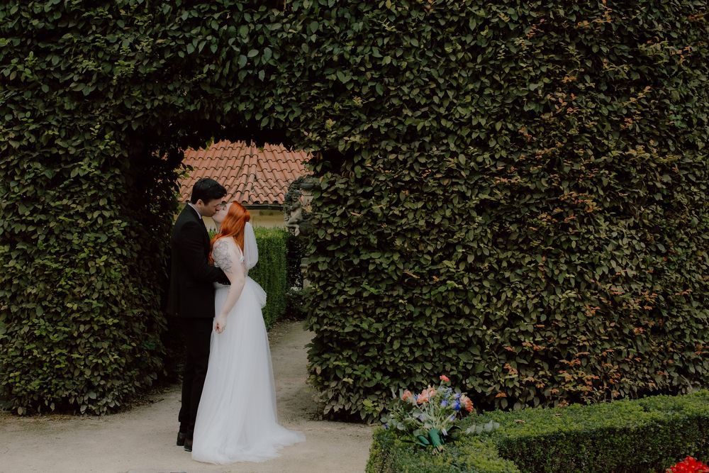 A beautiful bride and groom share a tender moment in front of an ivy-covered garden wall at their outdoor wedding celebration.