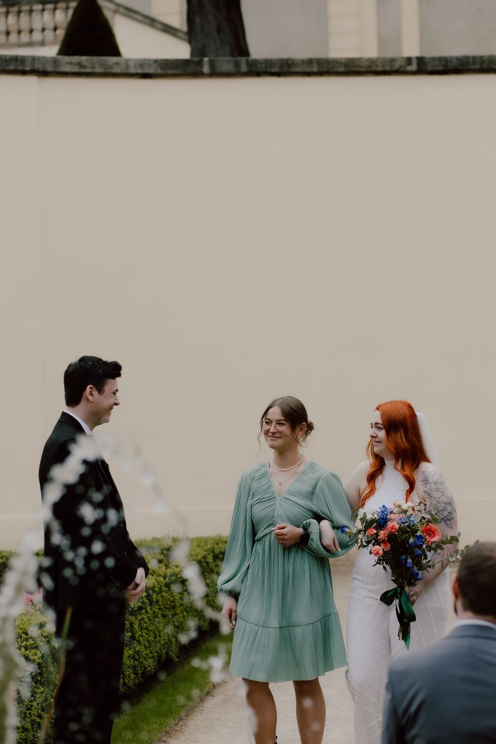 Wedding party interacting outdoors with bridesmaids in mint green dresses and bride carrying colorful bouquet.