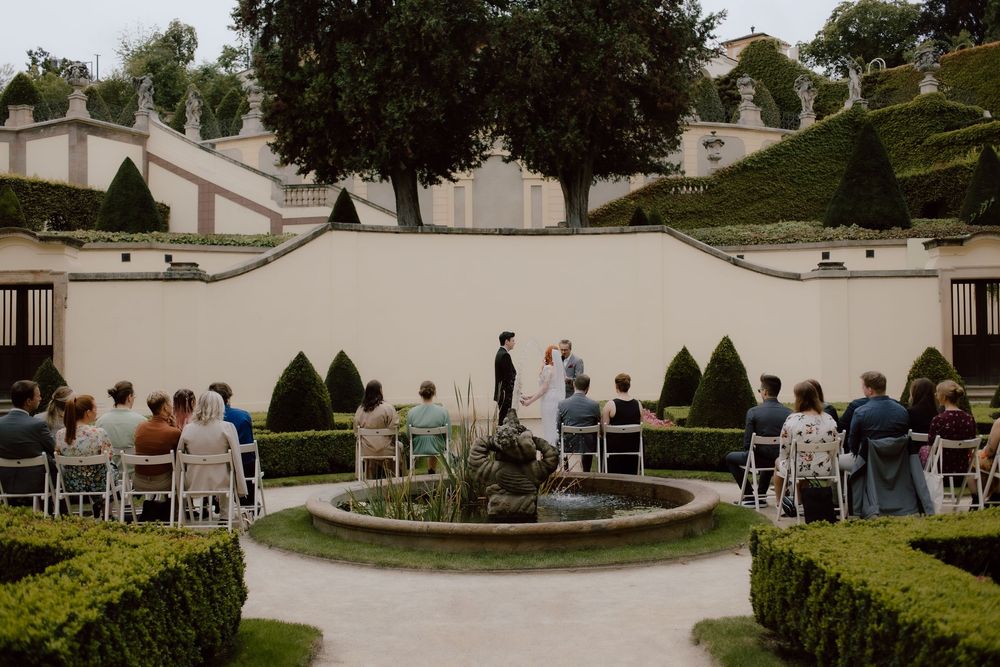 A scenic garden venue setup with white chairs and hedges for an outdoor wedding ceremony.