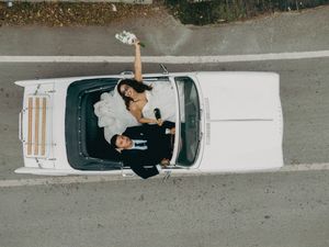 Aerial view of white vintage wedding car and couple from above.
