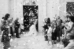 Wedding celebration with confetti being thrown in front of a white stone building.