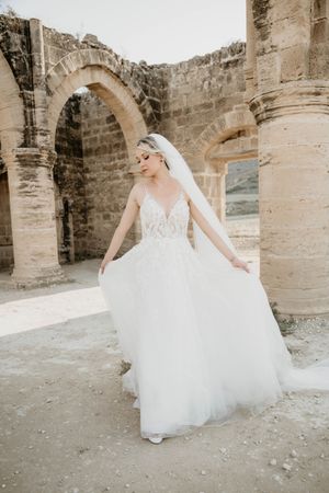 Elegant wedding dress with flowy tulle skirt photographed in ancient stone ruins with arched architecture.