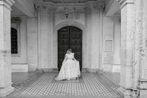 Elegant white archways and pillars form a colonnade in a historic building interior with checkered floor tiles.