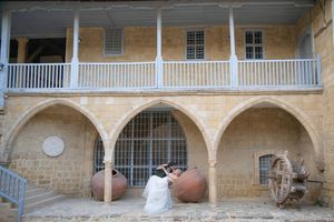 Historic stone corridor with white painted pillars and railing features decorative clay pots and vintage architecture.