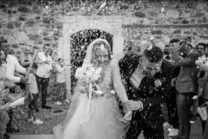 Wedding guests shower the newlyweds with confetti and rice as they exit the church in black and white photography.