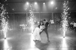Black and white photo of a couple sharing their first dance on a misty dance floor with sparkling fountains of light.