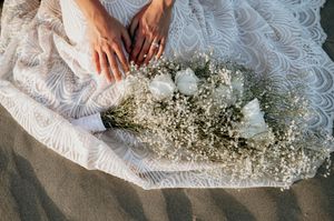 Close-up sequence showing a white lace dress being embellished with delicate baby's breath flowers.
