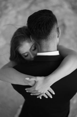 In a sequence of black and white photos, two people share intimate embraces and hold each other with quiet tenderness.