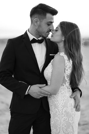A romantic black and white photo sequence captures tender kisses between a couple in wedding attire against a soft backdrop.