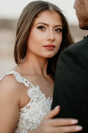 Close-up portrait shot of bride wearing an elegant white lace wedding dress with intricate floral detailing.