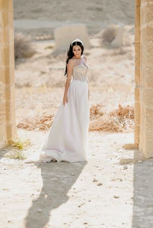 White dress flowing between architectural columns in soft natural light.