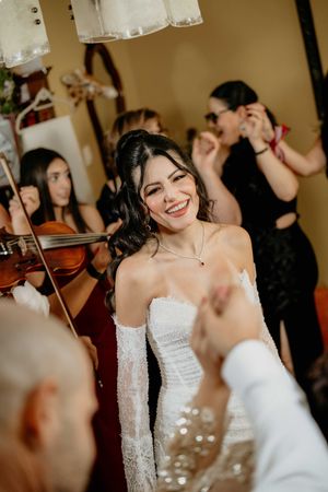 A bride in a white strapless dress laughs joyfully during a wedding celebration.