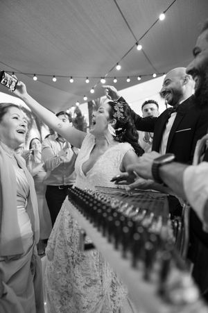 Wedding guests dancing and celebrating under a tent with string lights and joyful energy at an evening reception.
