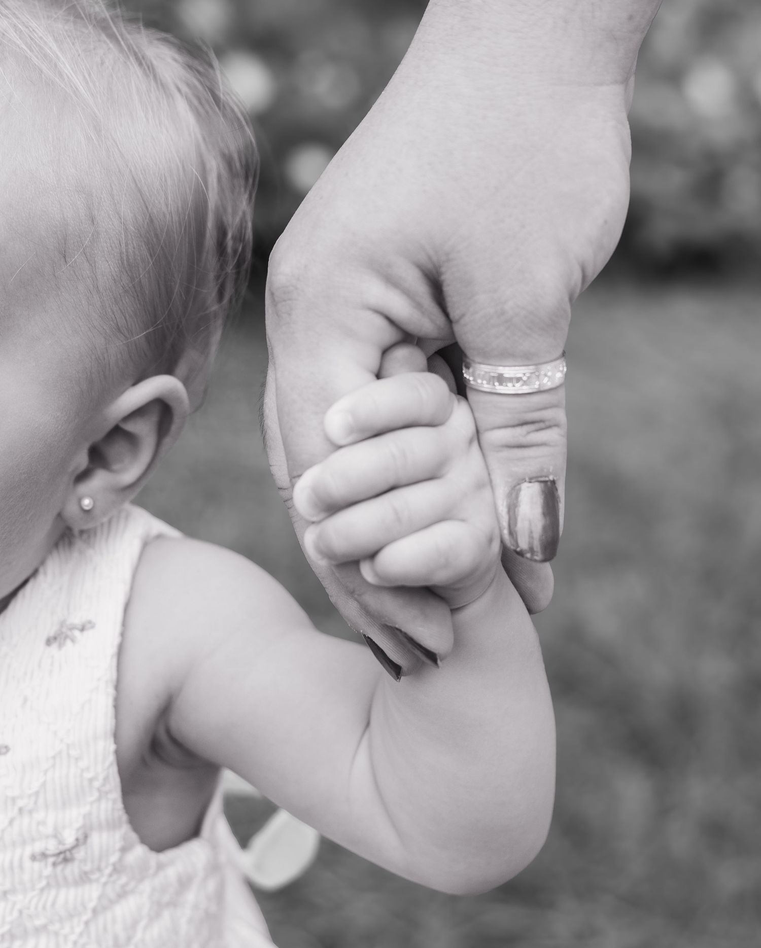 Black and white close-up images of hands gently holding a baby's arm.
