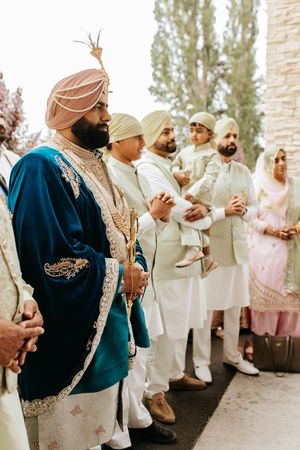 Wedding guests in traditional Sikh attire gathering outdoors, wearing turbans and formal ethnic clothing.
